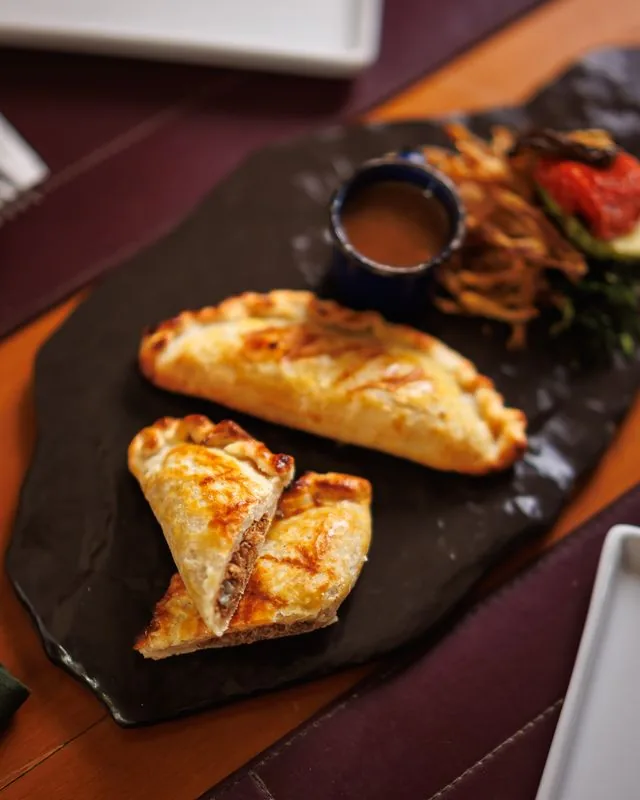 Dueto de empanadas servido na ardósia do ¡Vení! Parrilla