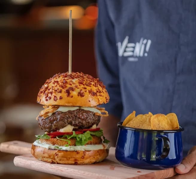 Veni Burguer servido com batatas no ¡Vení! Parrilla