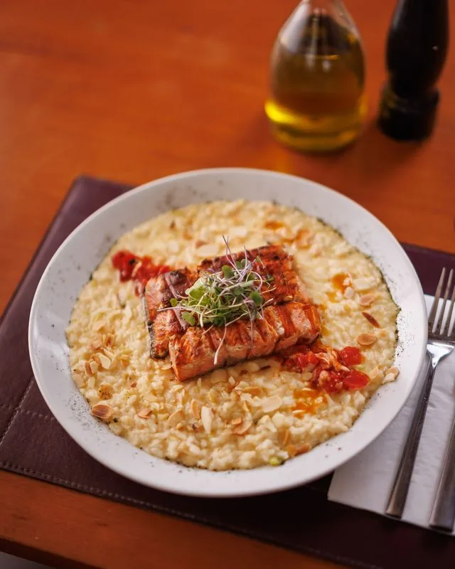 Salmão servido sobre risoto de amêndoas no ¡Vení! Parrilla